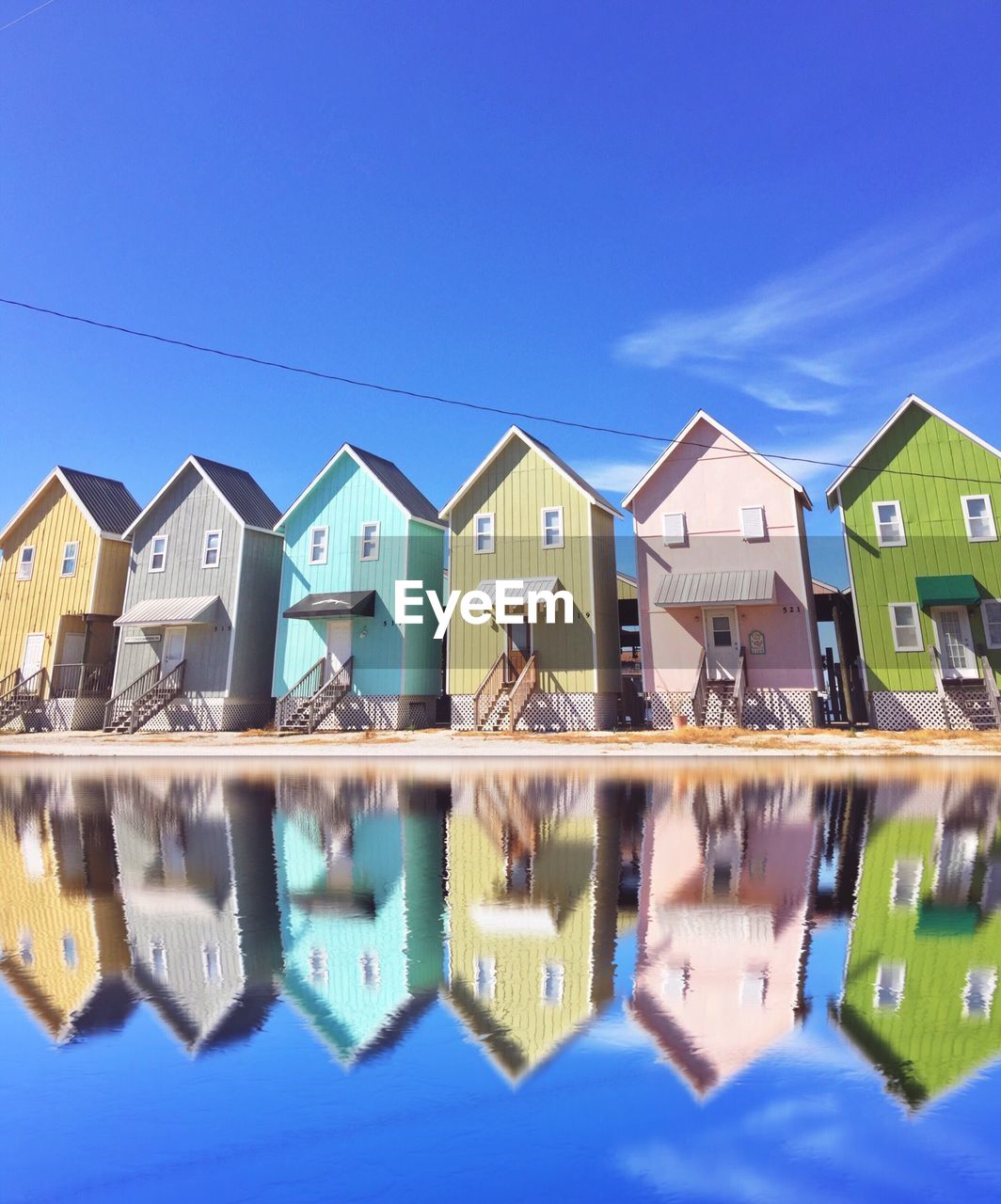 REFLECTION OF BUILDINGS IN SWIMMING POOL AGAINST CLEAR BLUE SKY