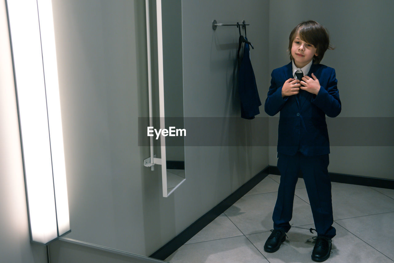 FULL LENGTH OF MAN LOOKING AT CAMERA WHILE STANDING IN MIRROR