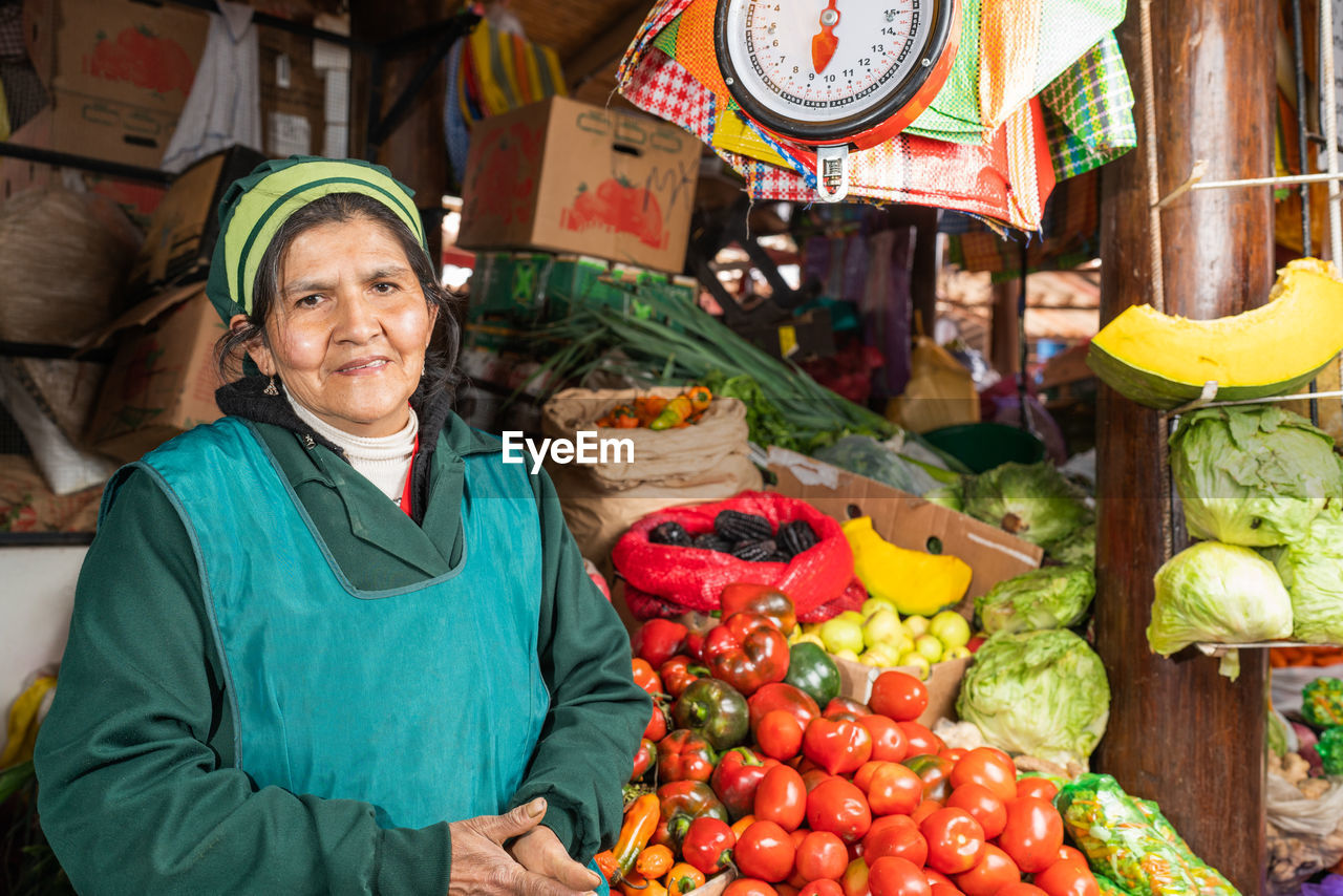 Peruvian female seller standing near stall with fresh tomatoes on itinerant fair