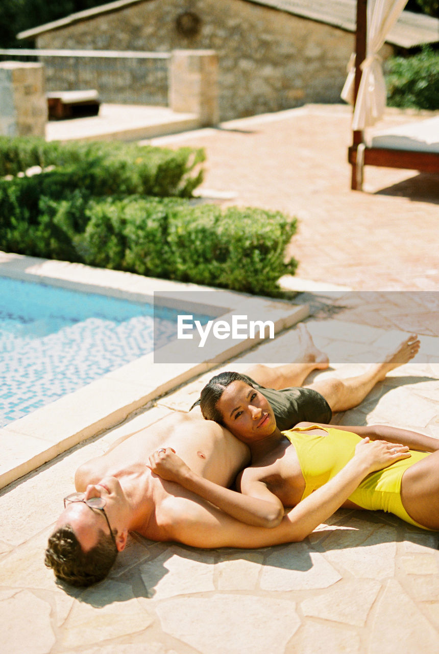 side view of shirtless young woman relaxing on poolside