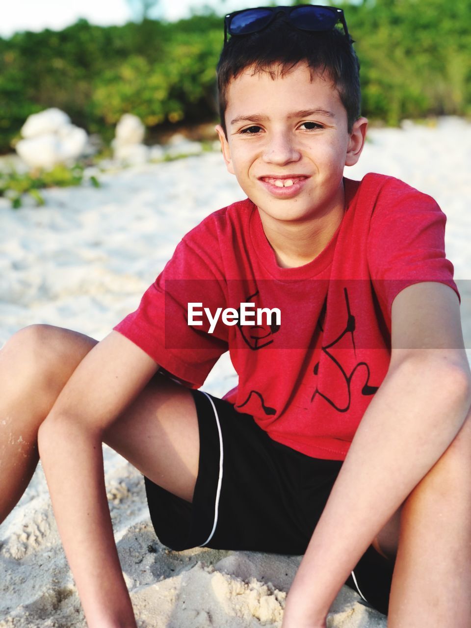 Portrait of smiling boy sitting on sand outdoors