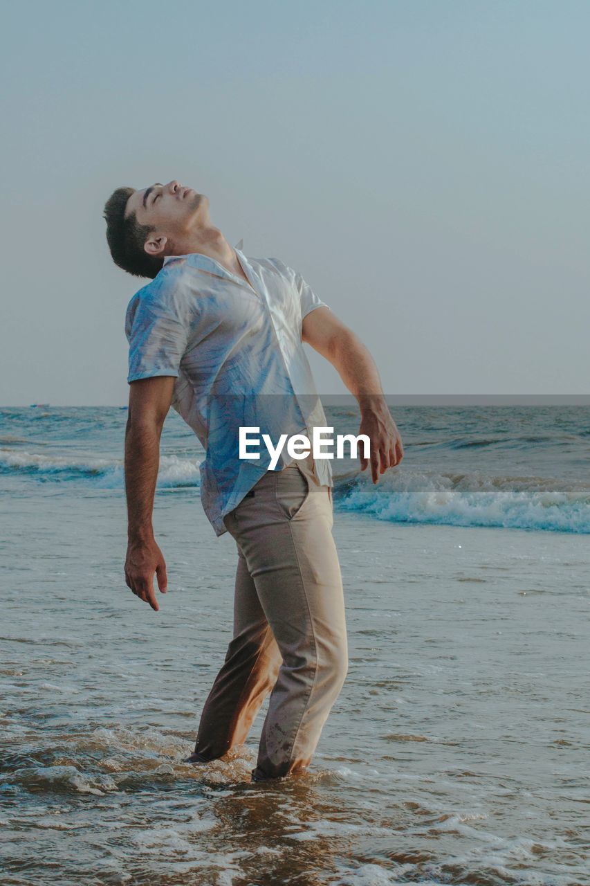 FULL LENGTH OF YOUNG MAN ON BEACH