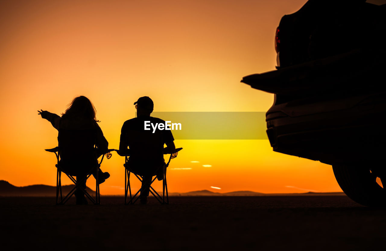 rear view of silhouette people on beach against sky during sunset