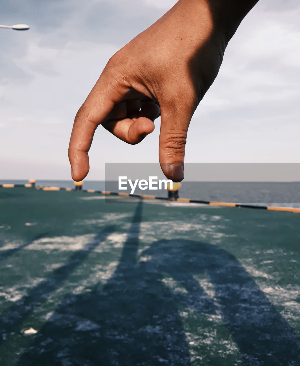 Midsection of person holding sea against sky