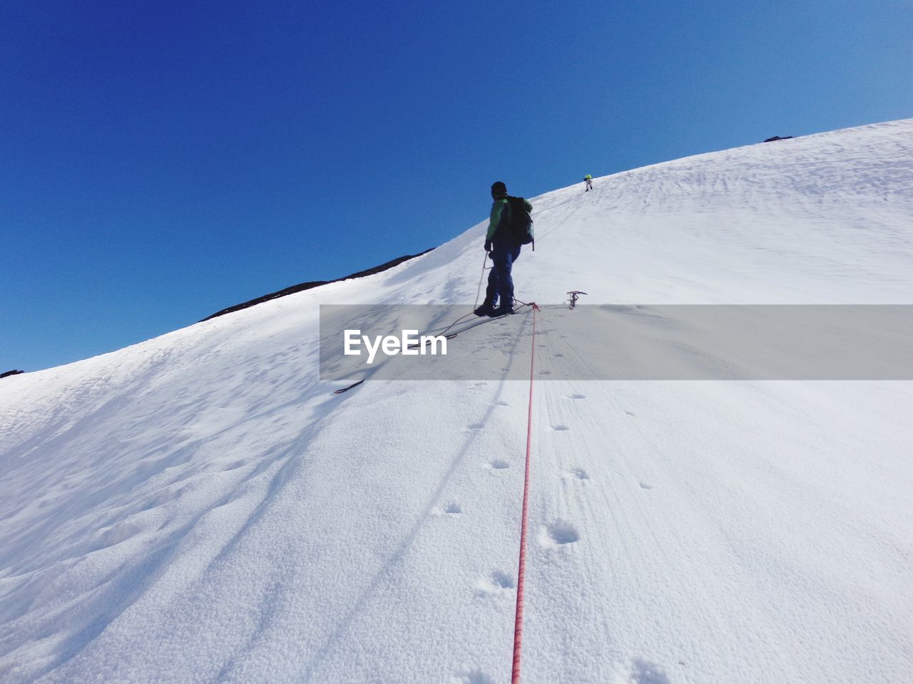 Man skiing on snowcapped mountain against clear sky