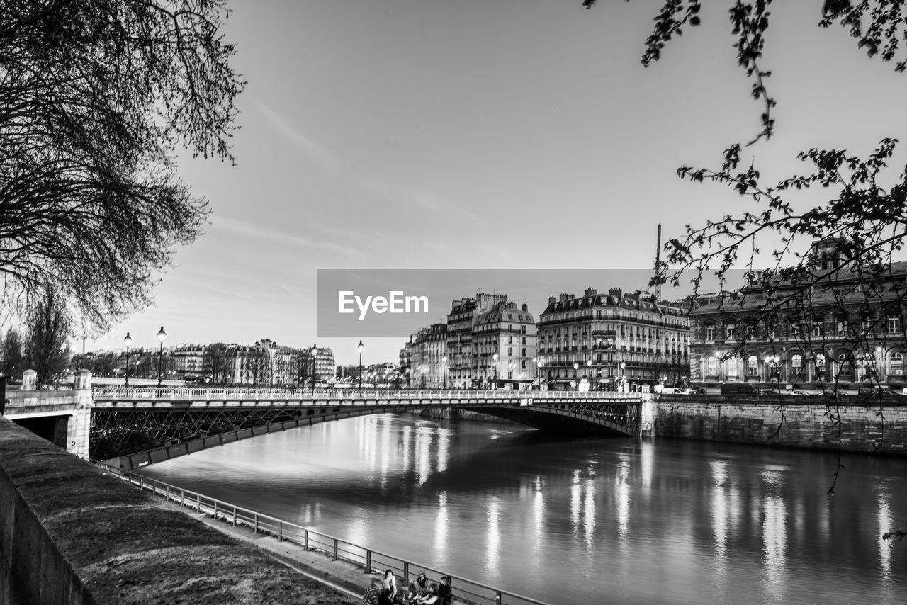 Bridge over river in city against sky paris black and white buildings seine evening lights