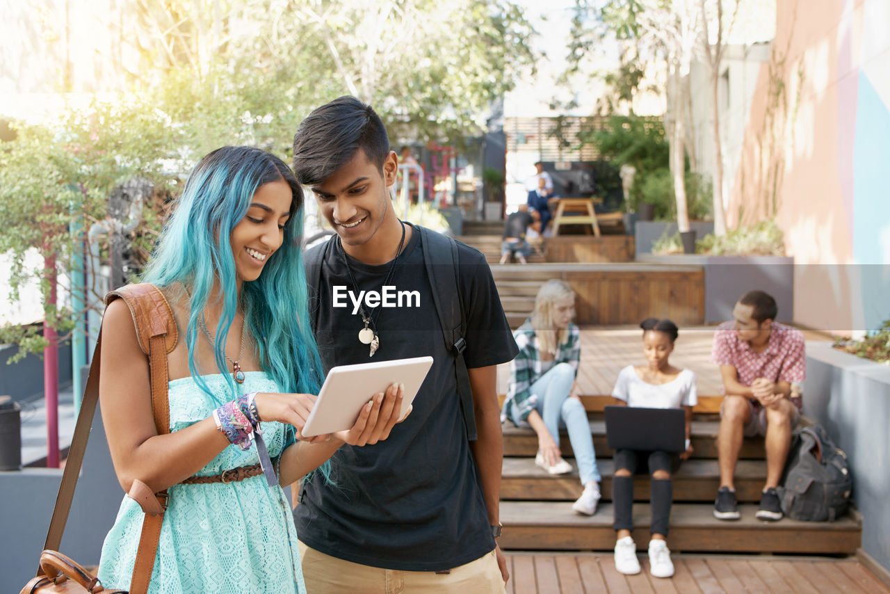 Friends looking at digital tablet in campus