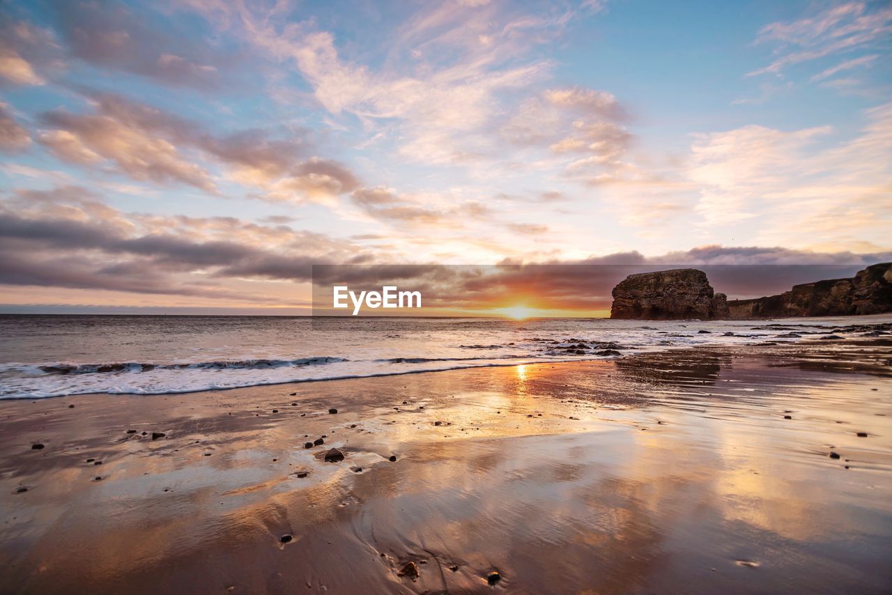 Scenic view of beach against sky during sunset