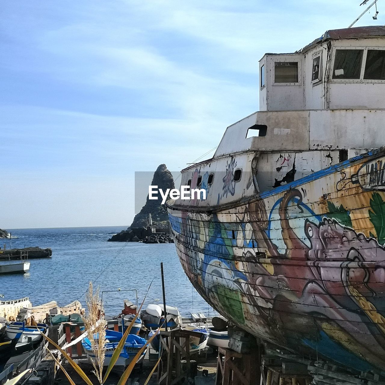 BOATS MOORED ON SEA SHORE AGAINST SKY