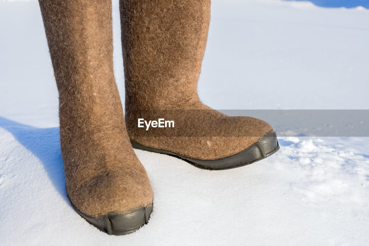 Rubber boots on snow covered field during sunny day