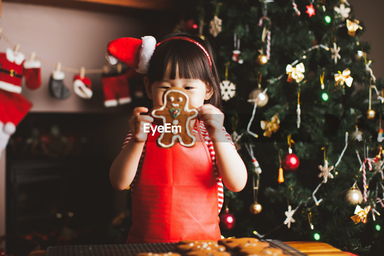 Girl with gingerbread cookie at home during christmas