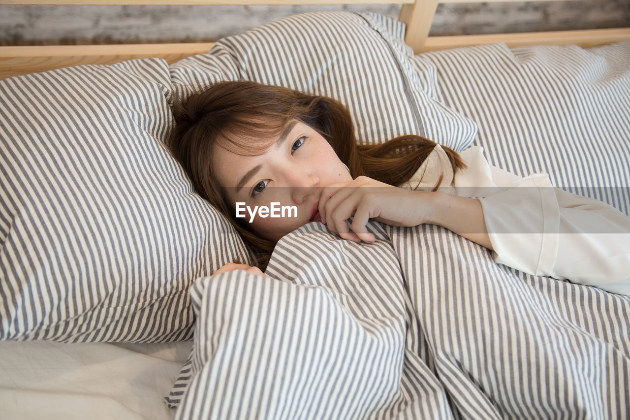 Portrait of young woman lying on bed