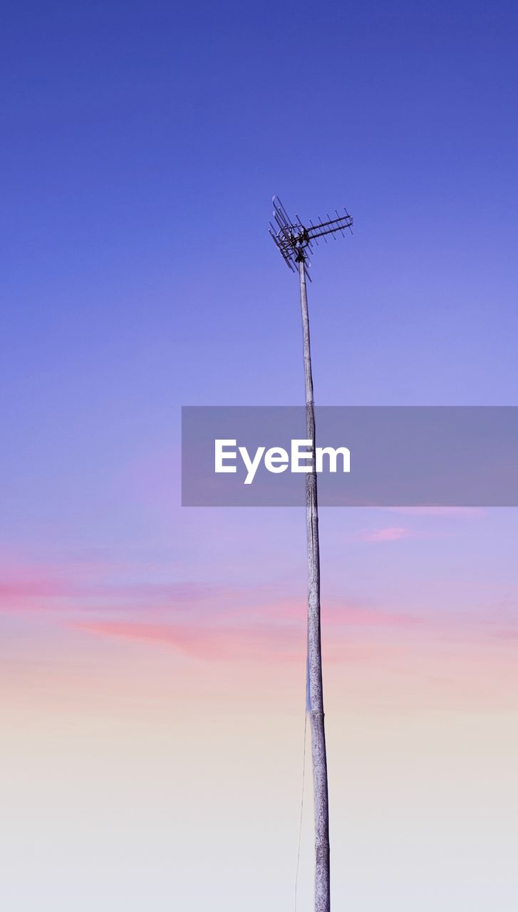 Low angle view of telephone pole against sky at sunset