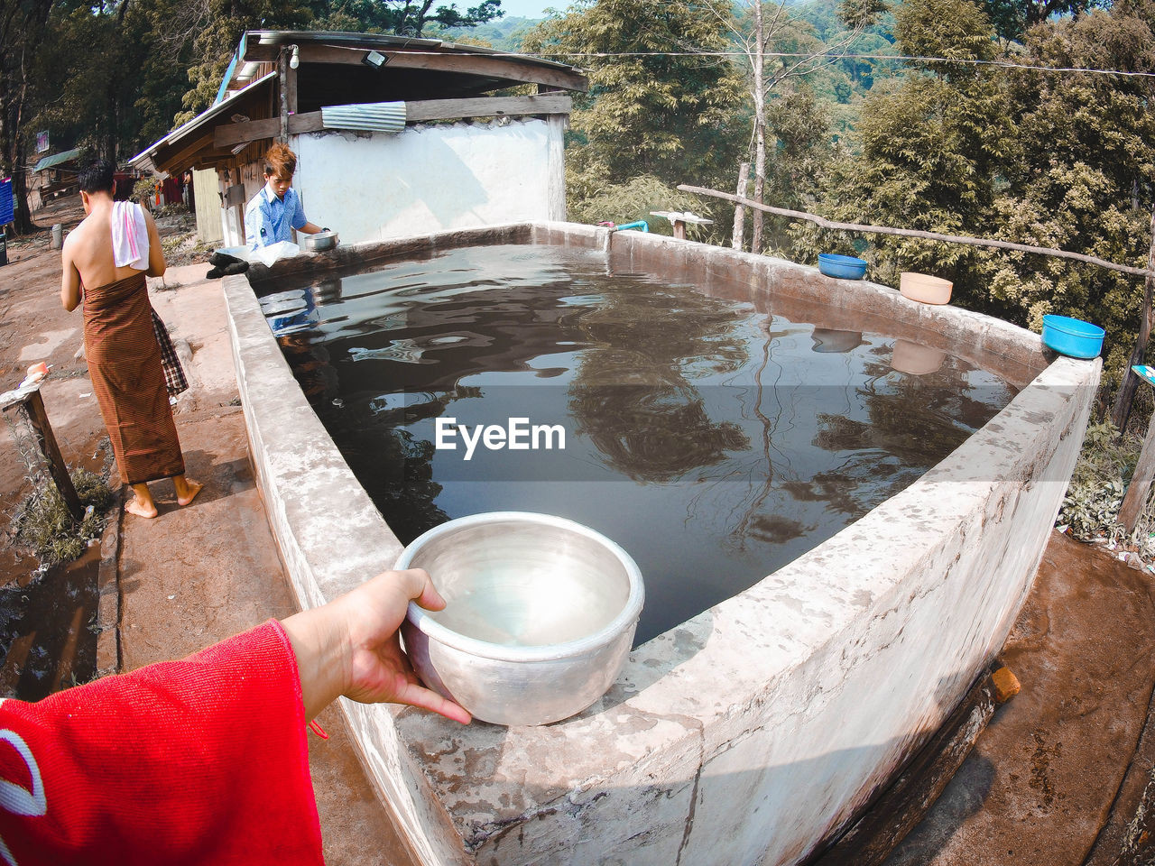 MIDSECTION OF WOMAN WORKING IN WATER AT CAMERA