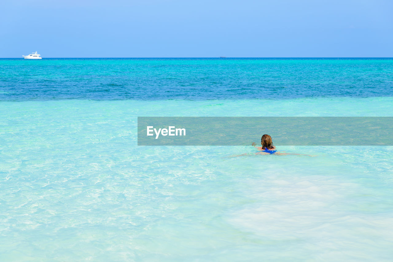 PERSON IN SEA AGAINST BLUE SKY