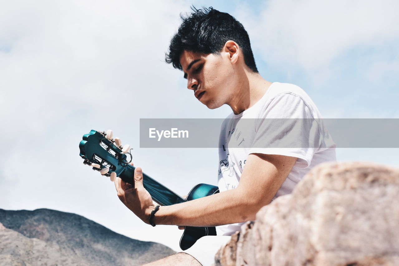 Man playing guitar against sky