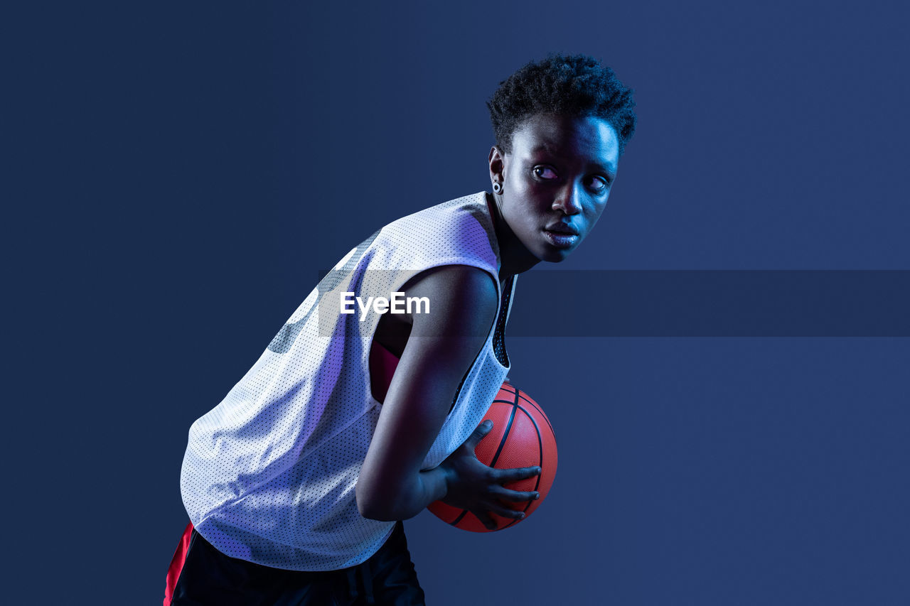 Black woman with basketball outfit in the studio using color gels and projector lights