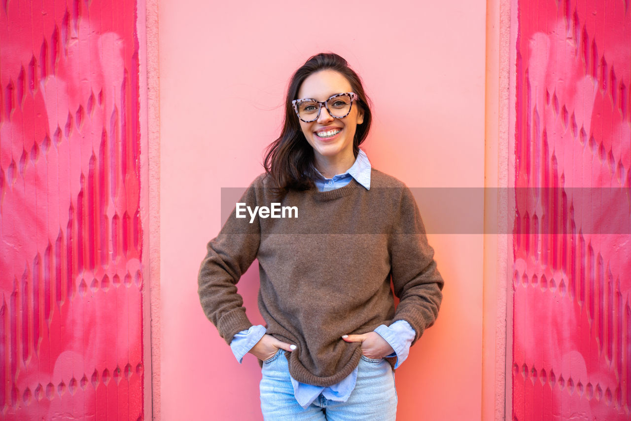 portrait of young woman standing against red wall