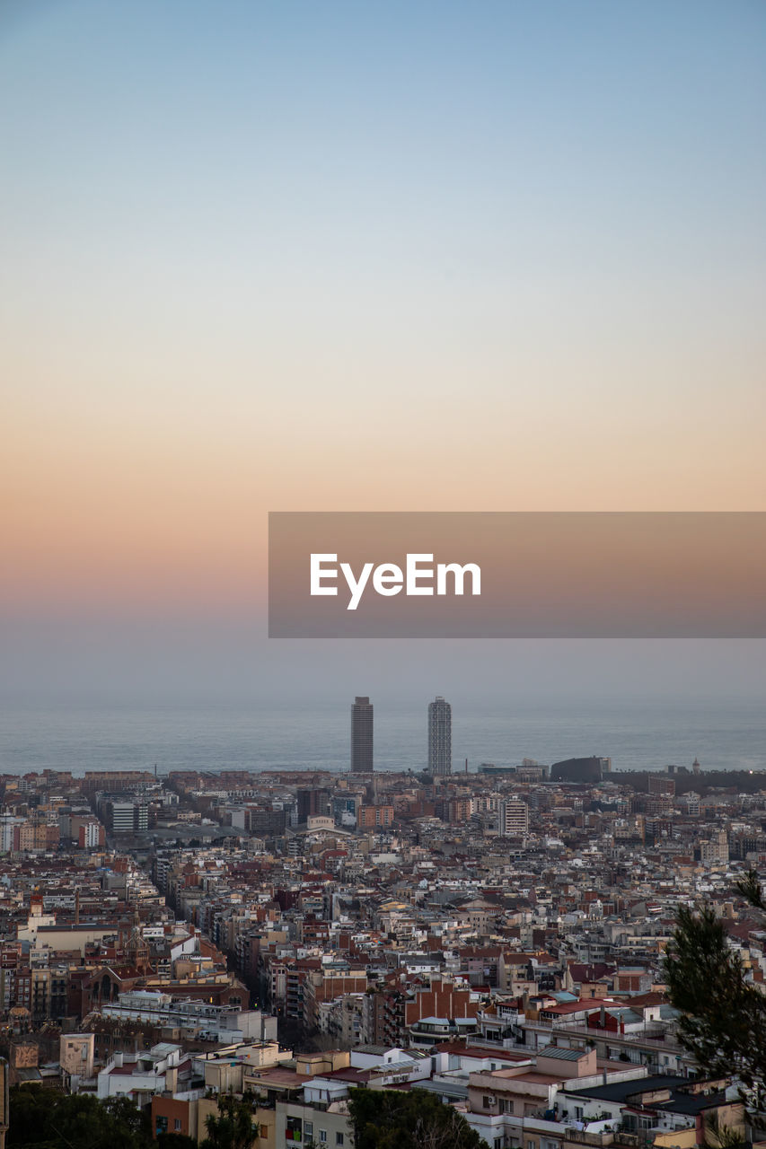 Aerial view of buildings in city against sky during sunset