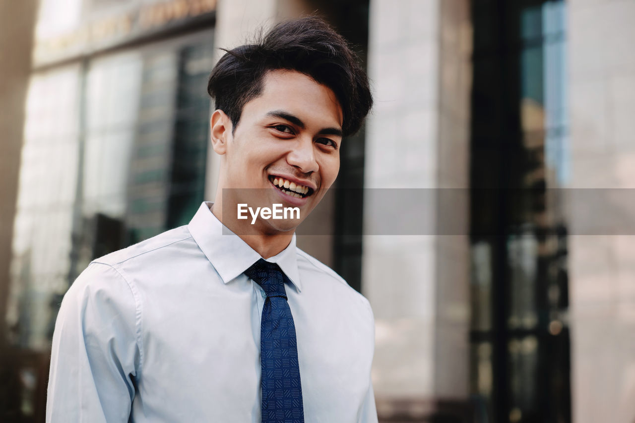 Portrait of smiling businessman standing outside building