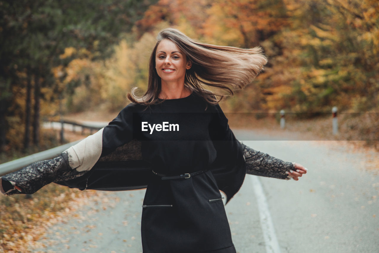 Portrait of woman standing on road during autumn