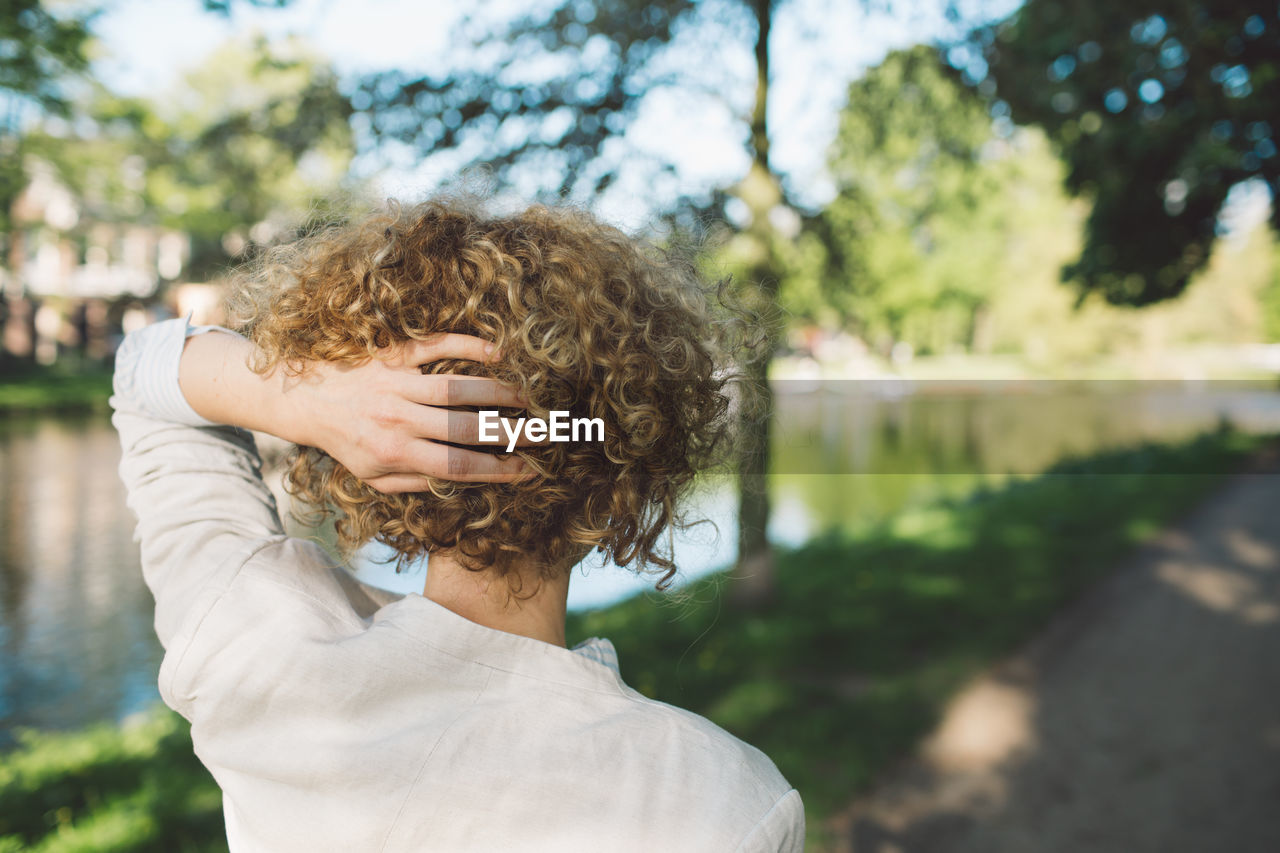 Rear view of woman with hand in hair standing at park