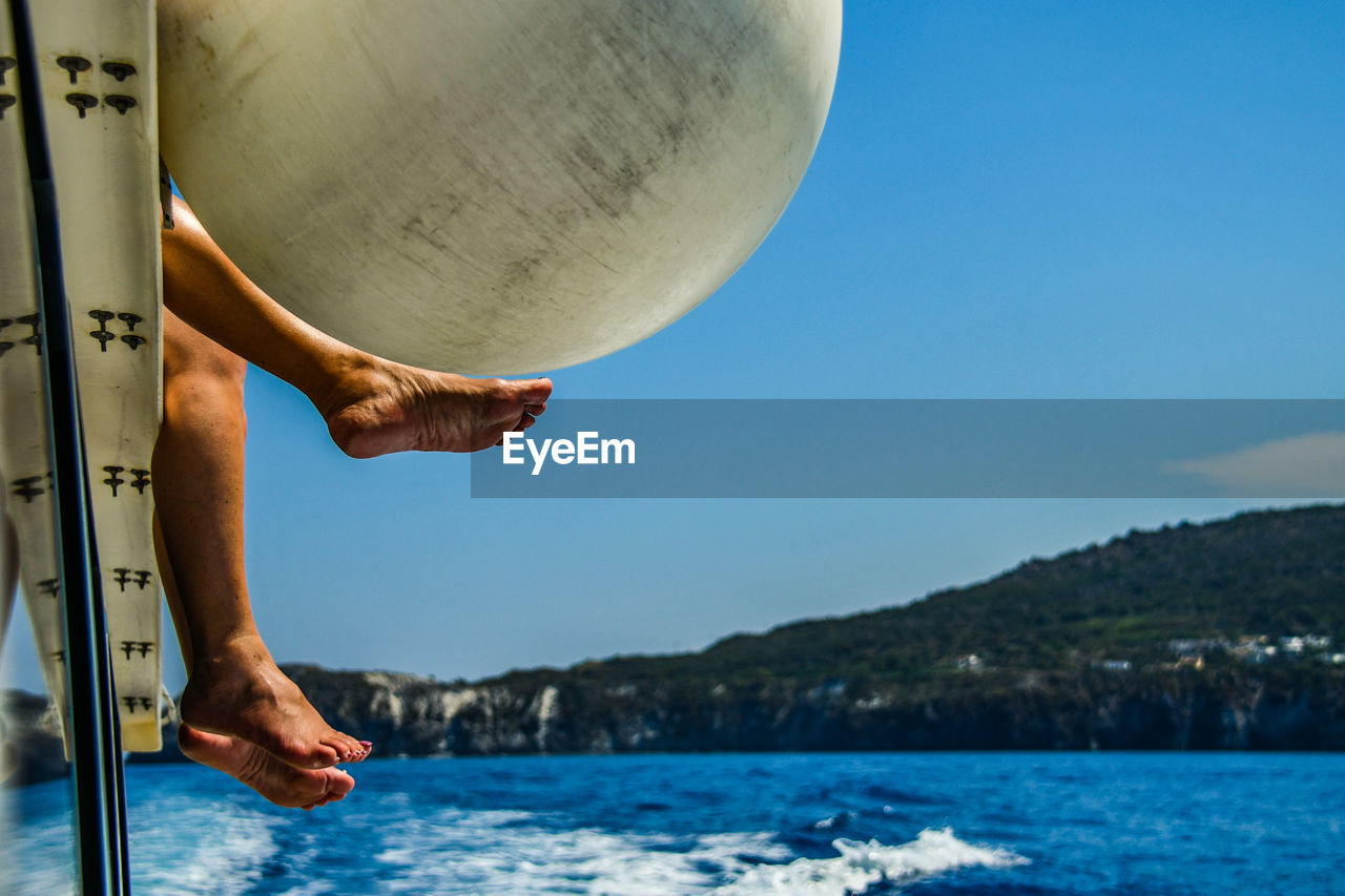 Low section of person in sea against sky