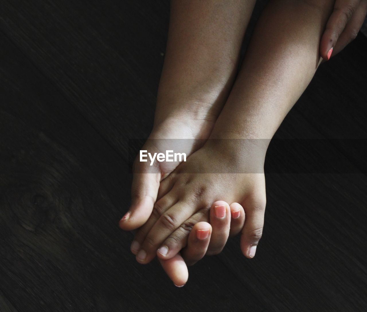 Cropped image of mother and son holding hands on table