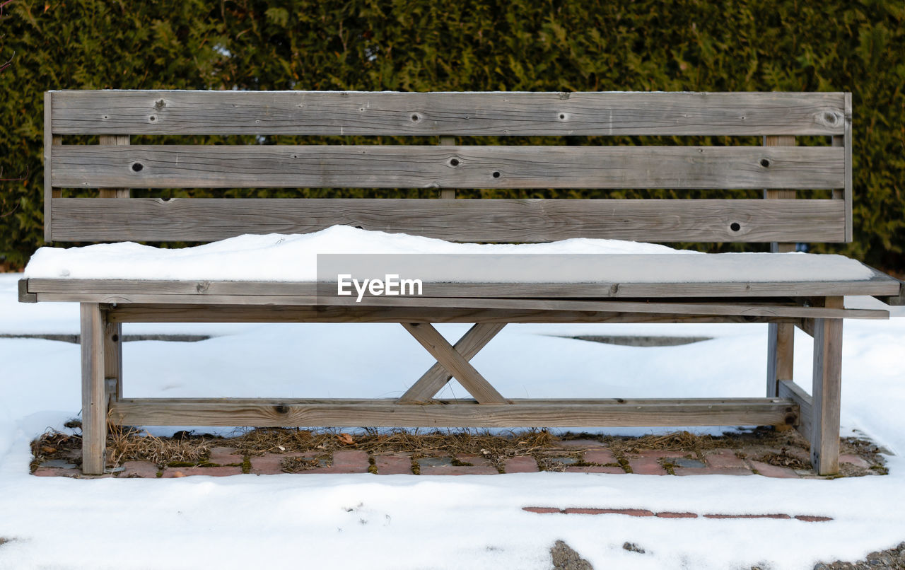EMPTY BENCHES ON SNOW COVERED FIELD