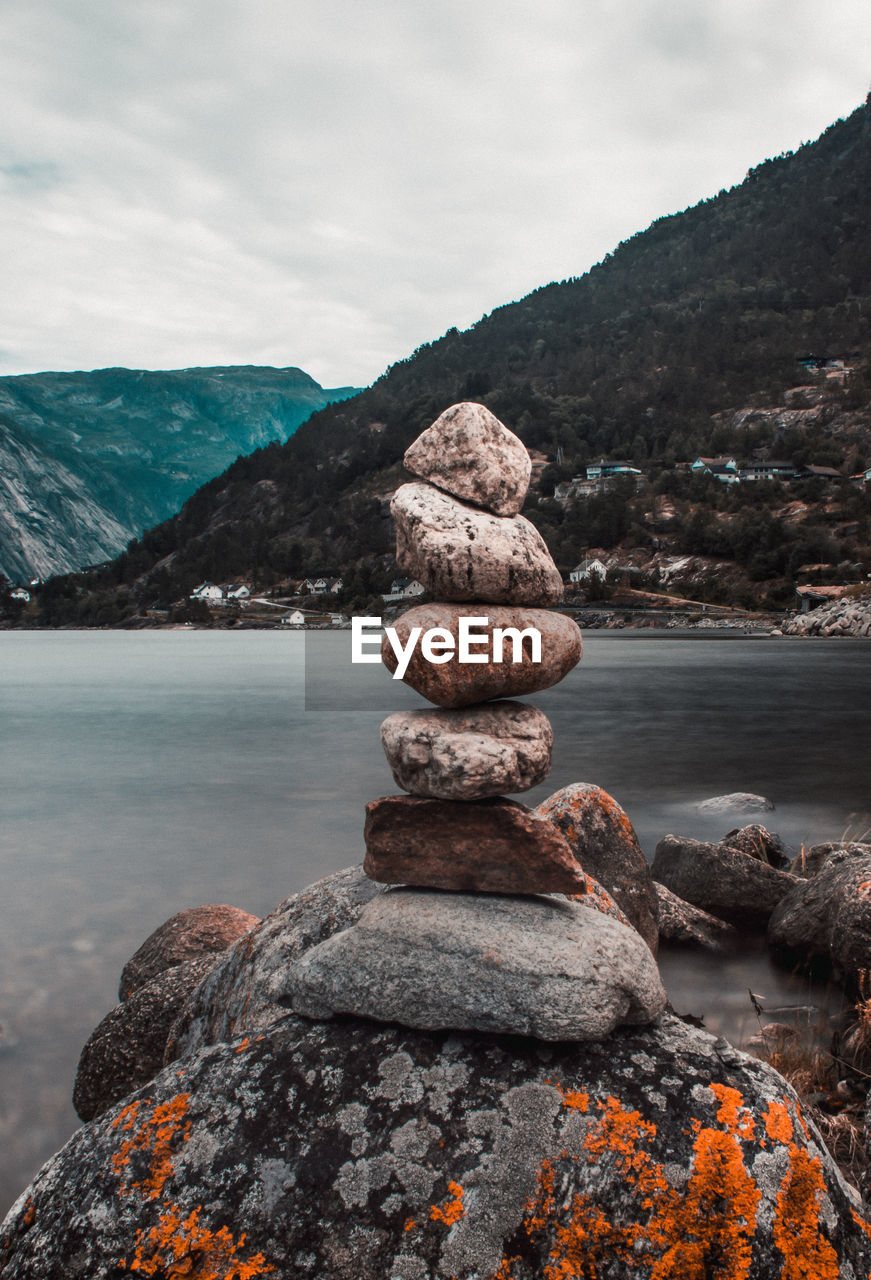 Stack of stones on rock against sky