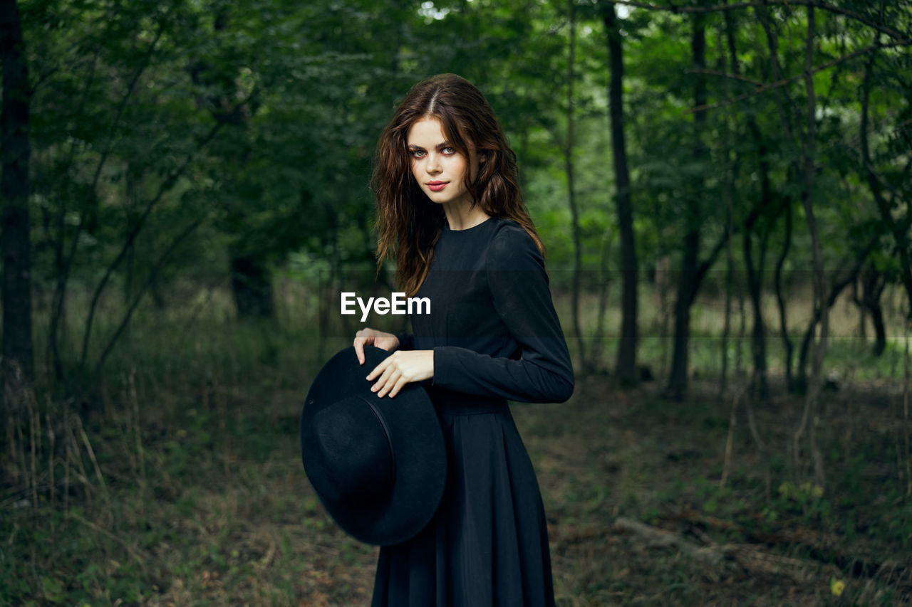 young woman looking away while standing in forest