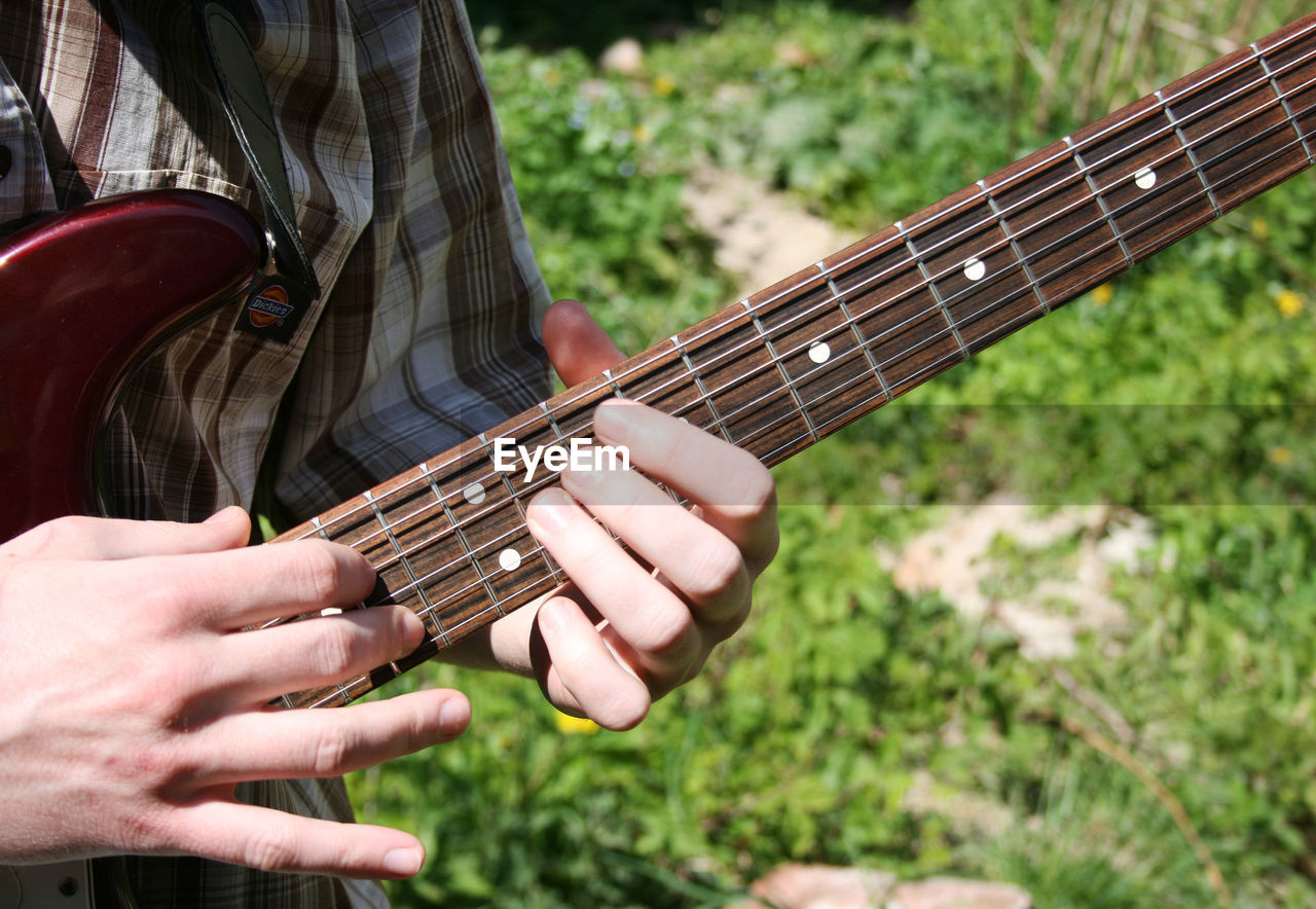 Midsection of man playing guitar