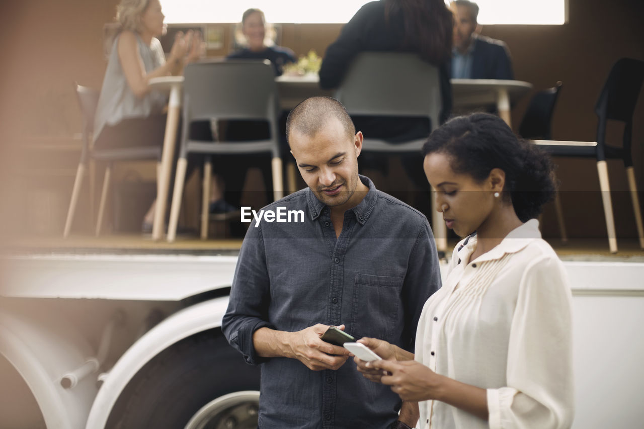 Business people using mobile phones with colleagues and portable office truck in background