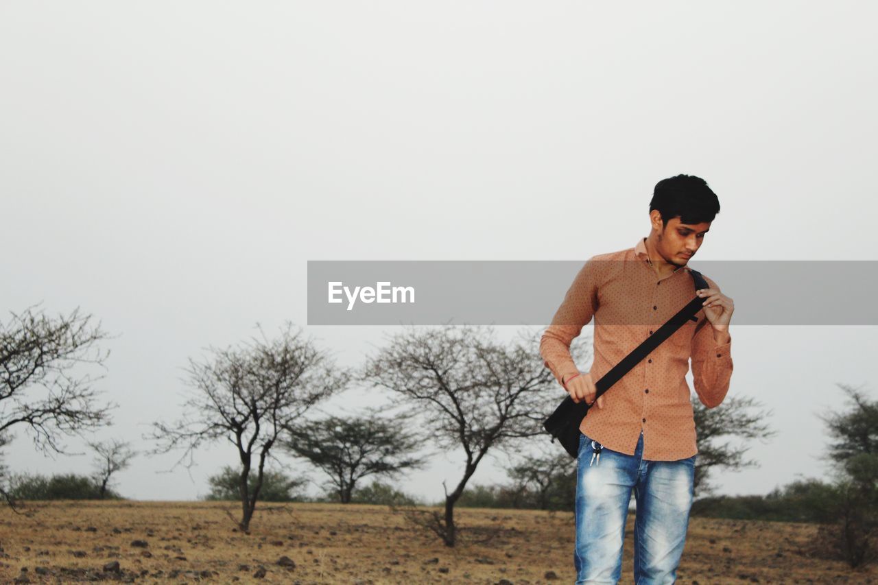 Young man standing on field against sky
