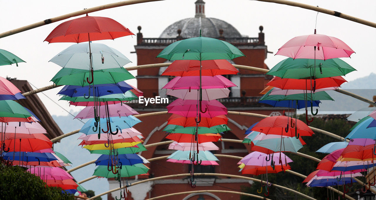 MULTI COLORED UMBRELLAS HANGING OUTSIDE BUILDING