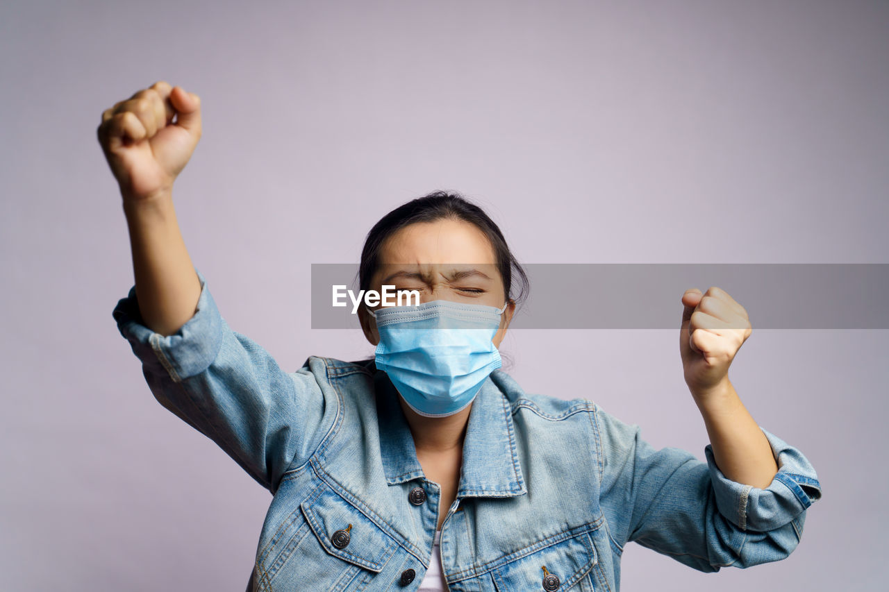 Young women wearing face mask against wall