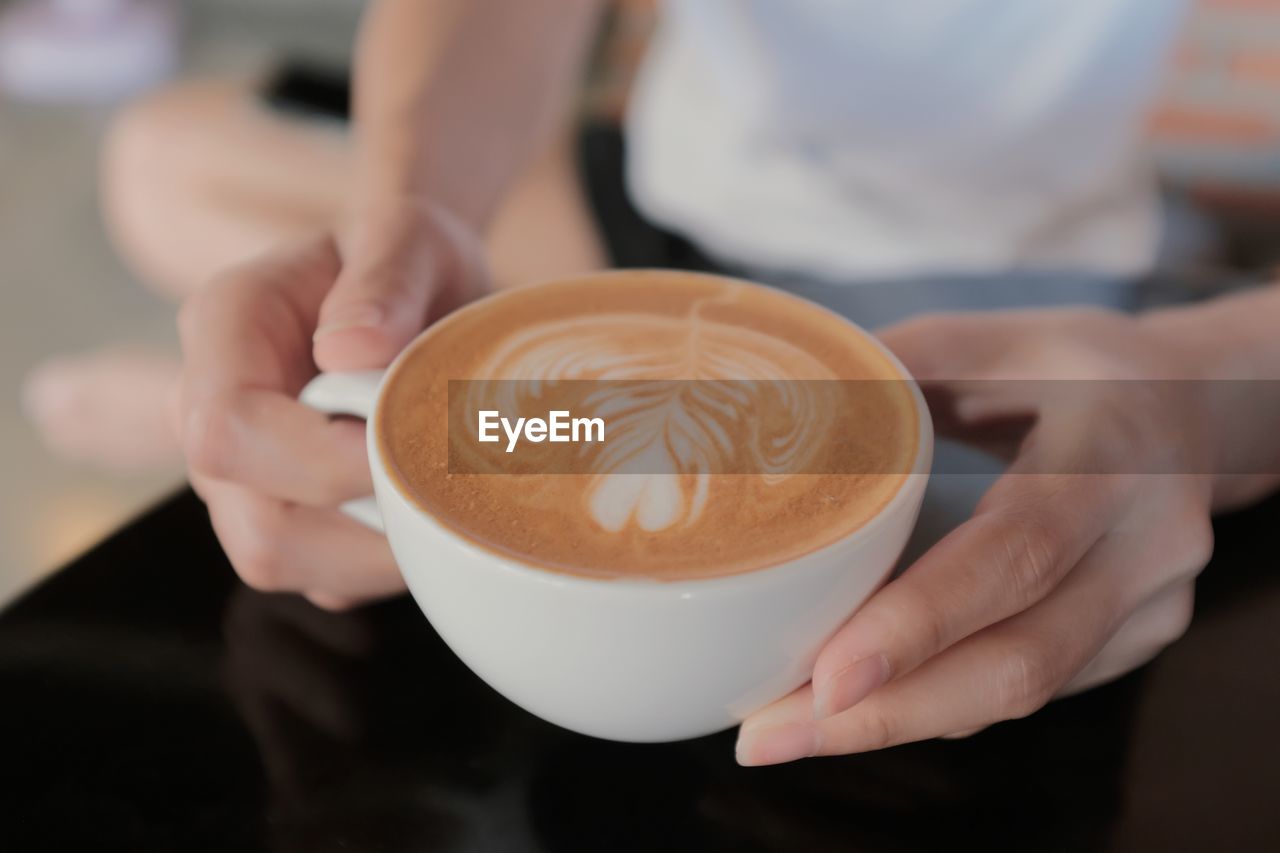 MIDSECTION OF WOMAN HOLDING COFFEE