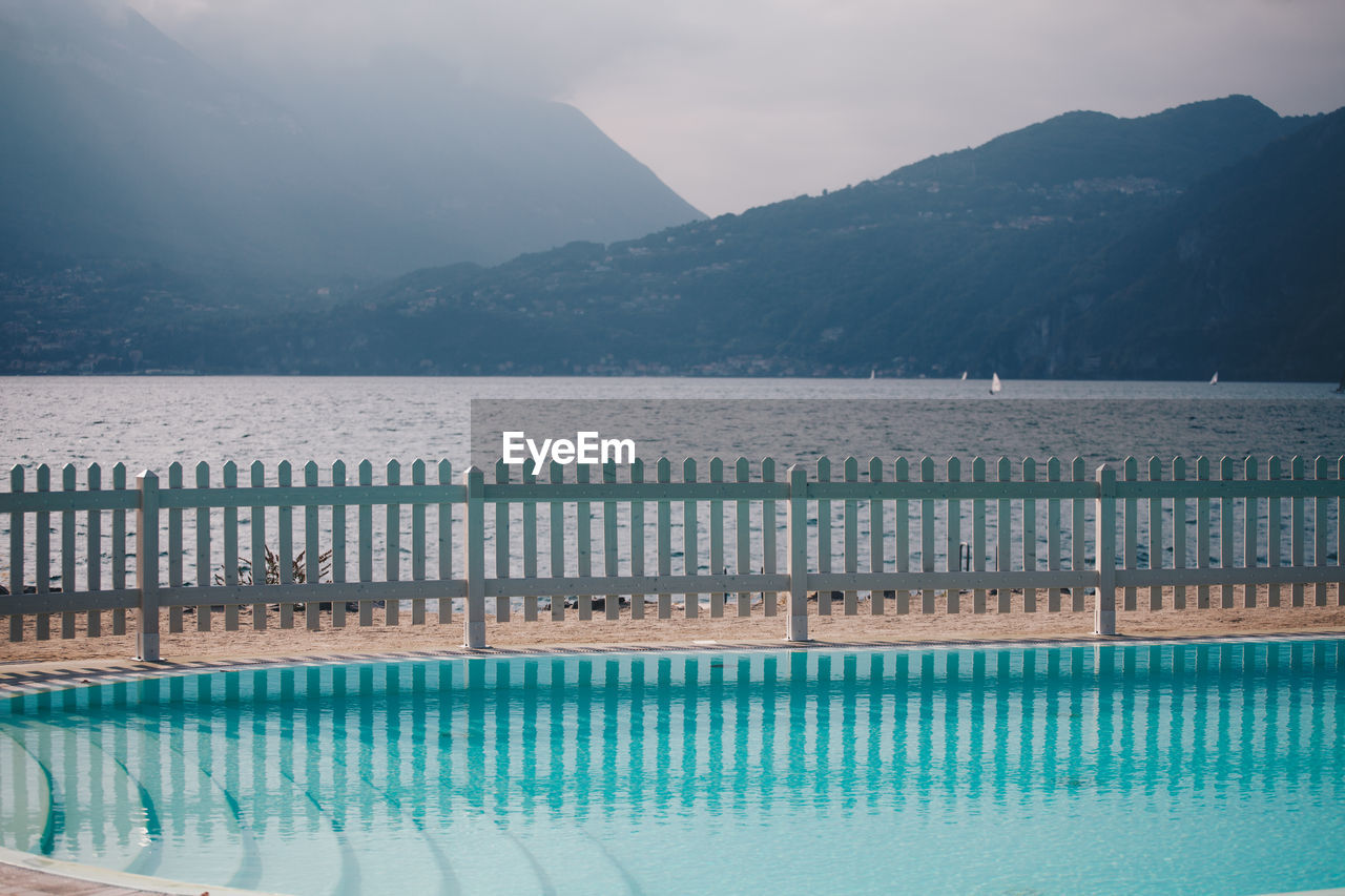 Swimming pool by lake against mountains