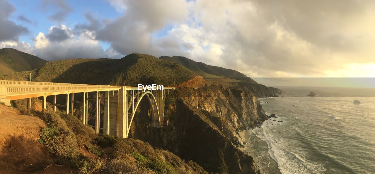 Bixby creek bridge and sea against cloudy sky 