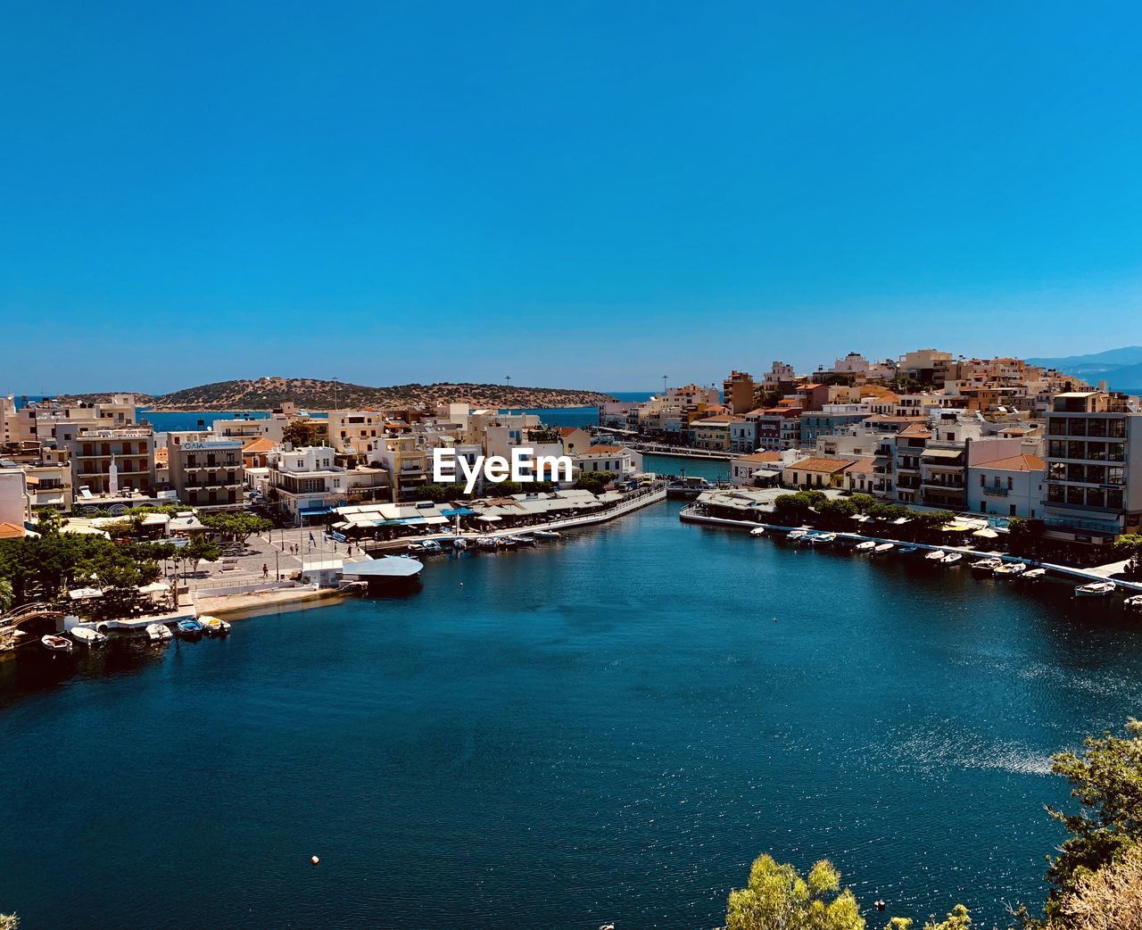 High angle view of sea and buildings against clear blue sky