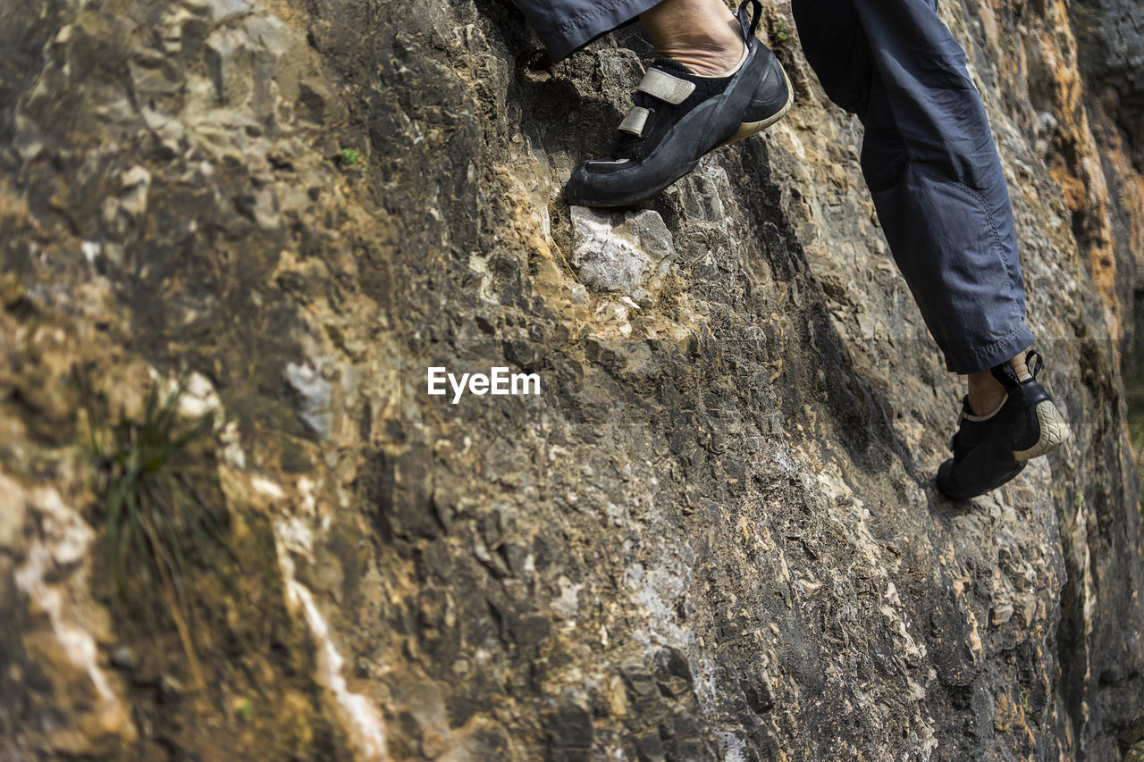 Low section of man climbing on rock