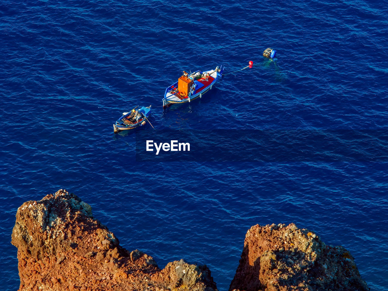 Fisherman catching a fish in the morning, above view from cliff. santorini, cyclades, greece