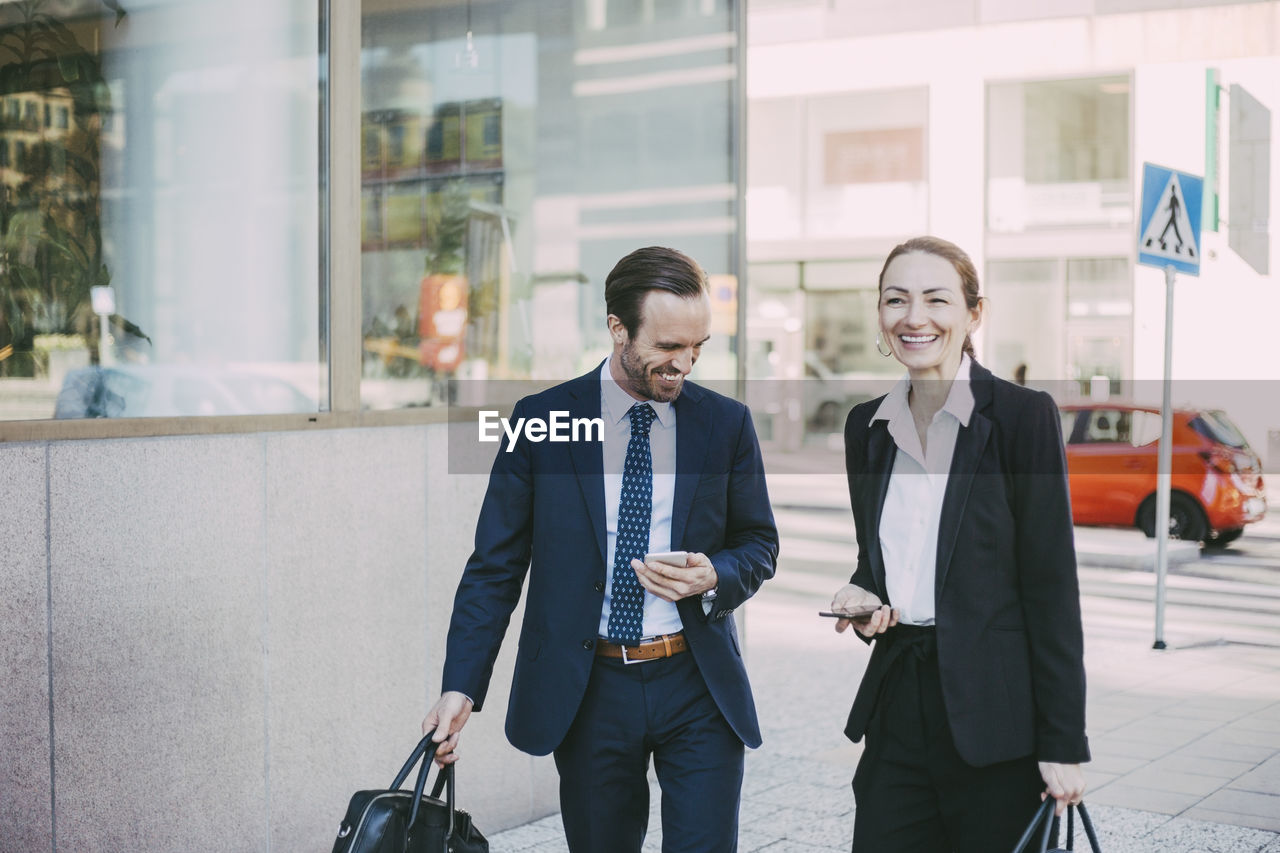 Happy male and female professionals in city