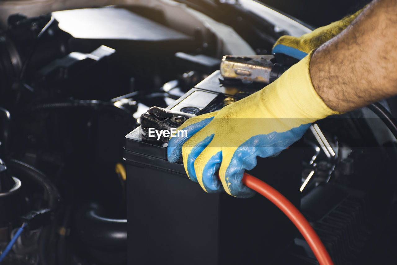 Auto mechanic clamping the charger cable to the car battery,accumulator charging