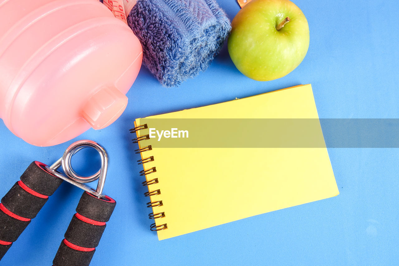 Directly above view of exercise equipment and apple on blue background