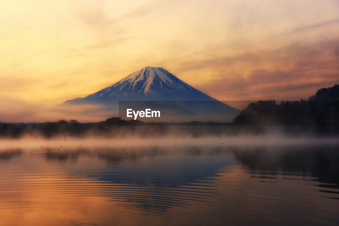 Mountain fuji with reflection and mist on water of lake shoji shojiko at sunrise, yamanashi, japan.