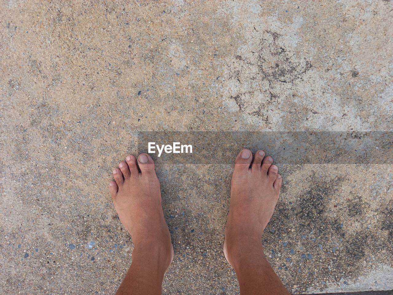 low section, human leg, one person, beach, barefoot, sand, high angle view, standing, land, personal perspective, limb, lifestyles, human foot, day, leisure activity, directly above, nature, hand, soil, adult, human limb, outdoors, women, toe, holiday, vacation, sunlight, trip, water