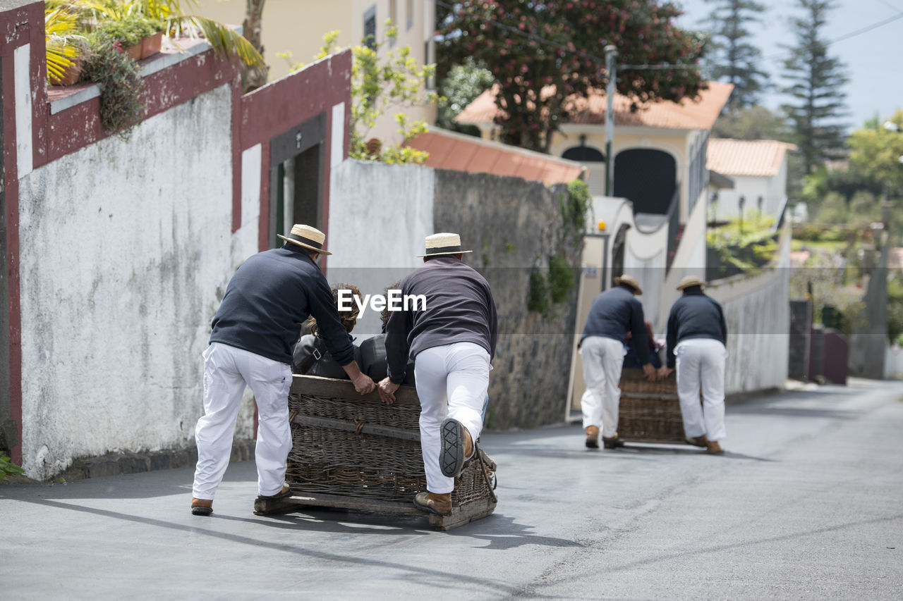 REAR VIEW OF PEOPLE WALKING ON FOOTPATH