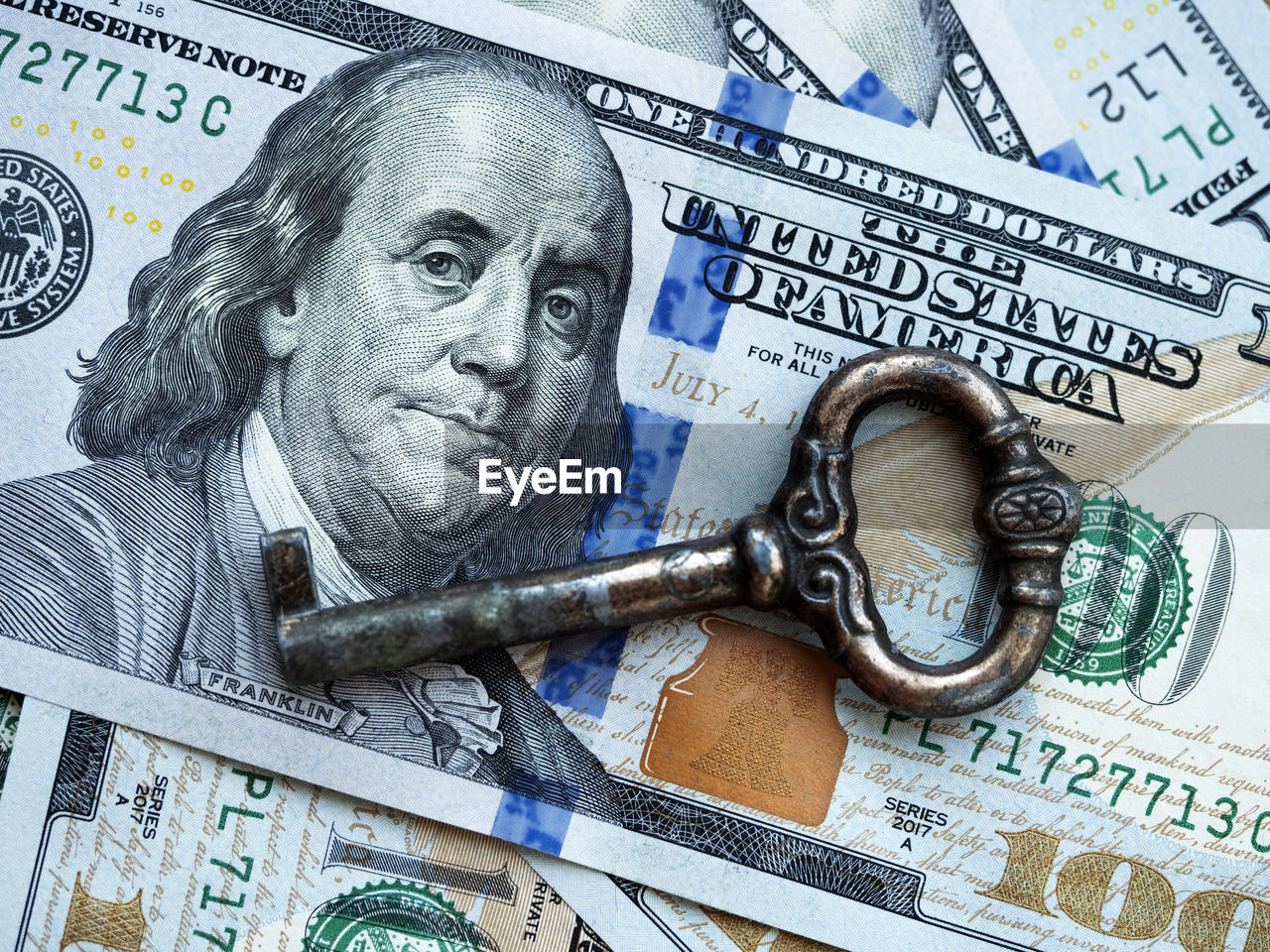 In this photo illustration old copper desk drawer key on the background of a 100 dollar bills