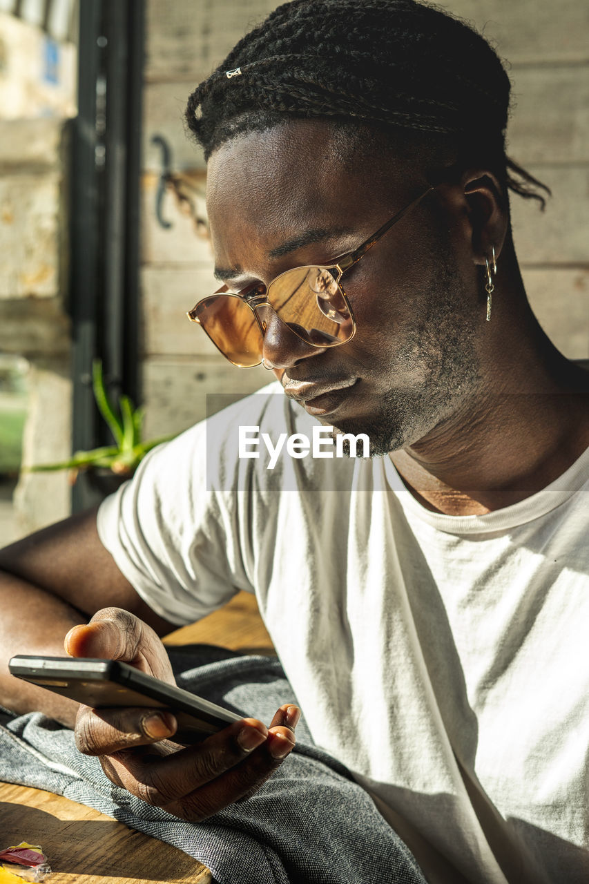 Young man using phone while sitting at table in cafe